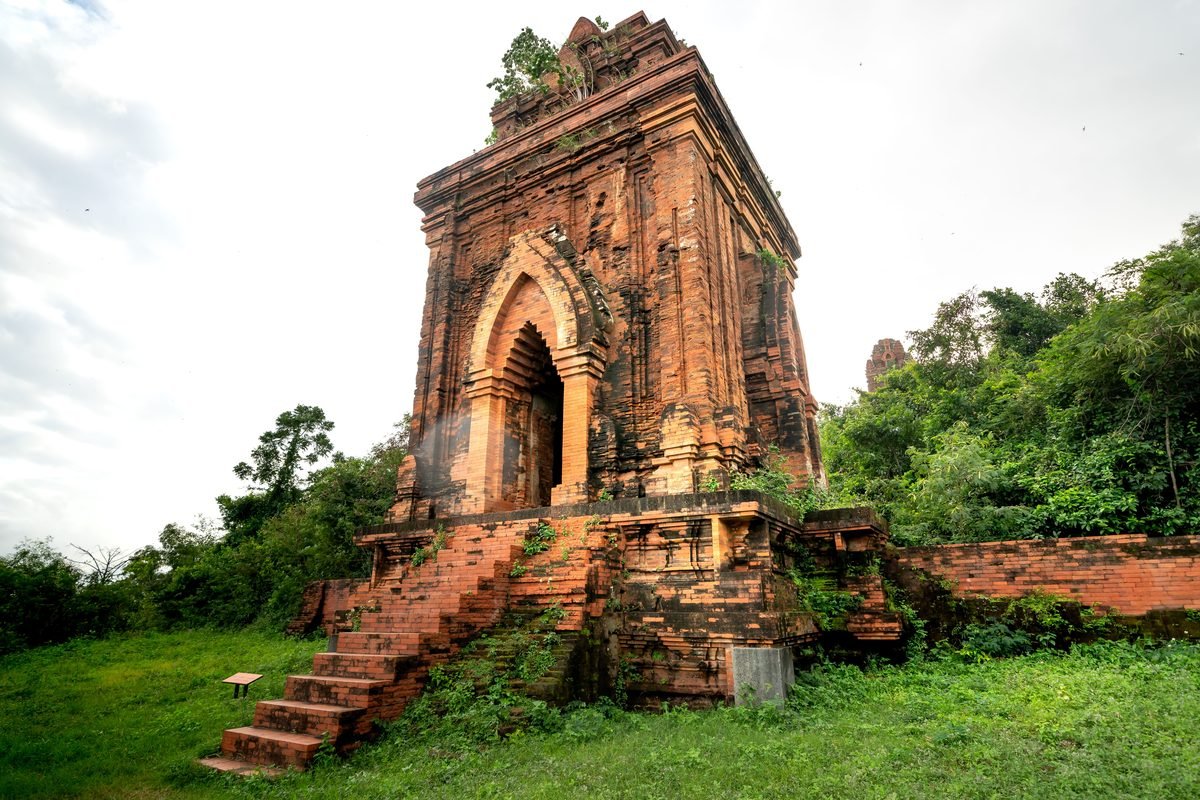 Historic red brick temple structure surrounded by greenery