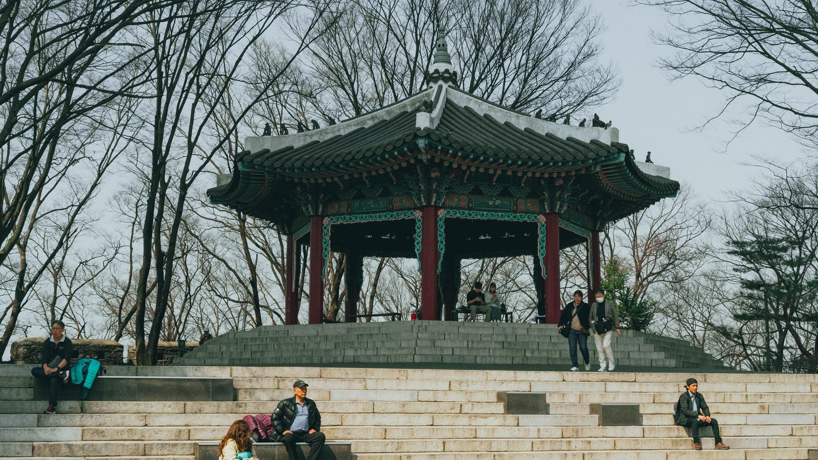 Traditional pavilion and people relaxing on stone steps at Namsan Park in Seoul