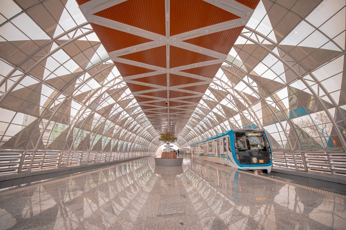 Modern train station platform with a glass roof architecture and blue train.