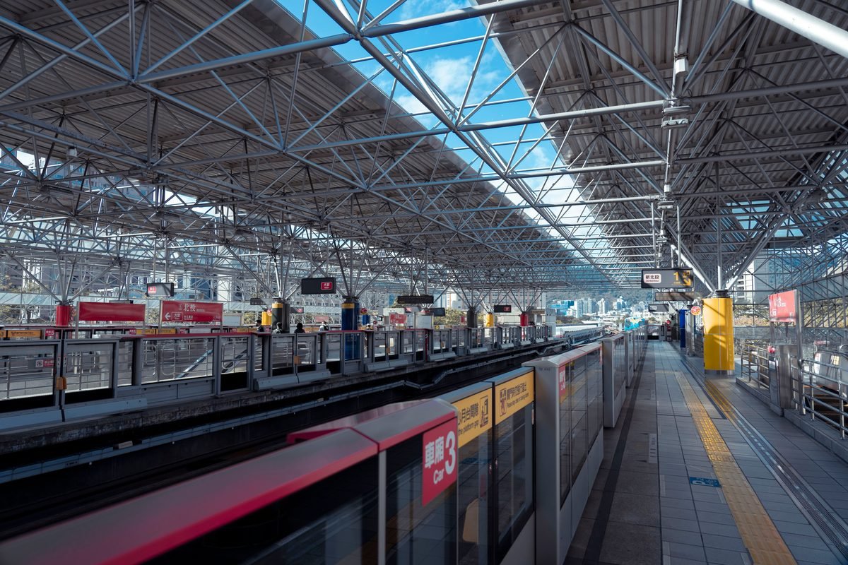 Spacious modern train station with lattice roof and empty platform.