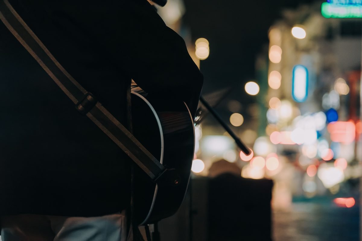Street musician performing with an acoustic guitar at night