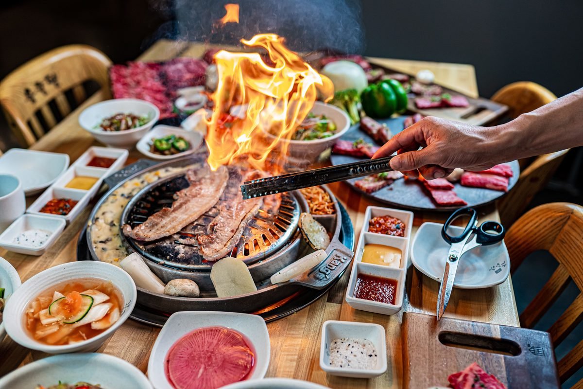 Korean barbecue with flames and side dishes on a table