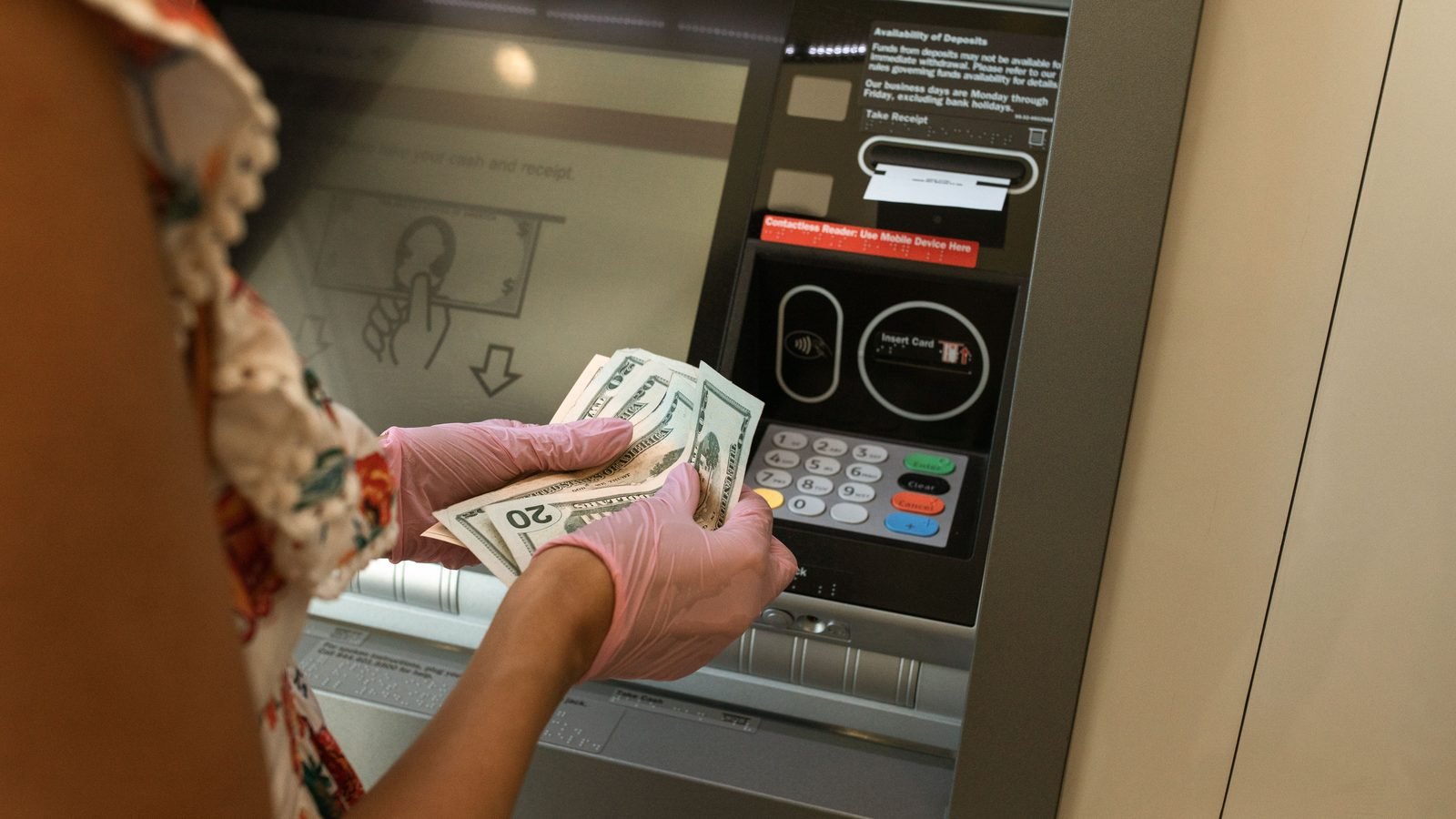 Person withdrawing money from ATM with gloves