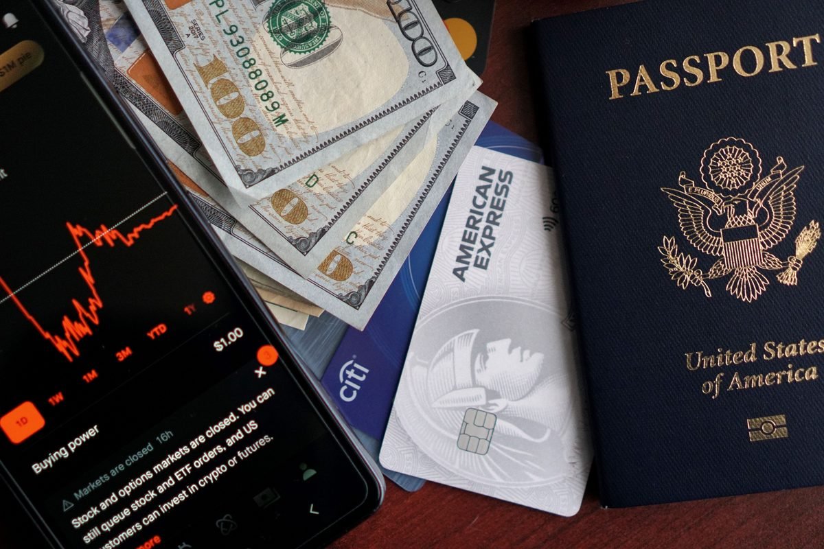 Smartphone showing financial charts next to passport and credit cards