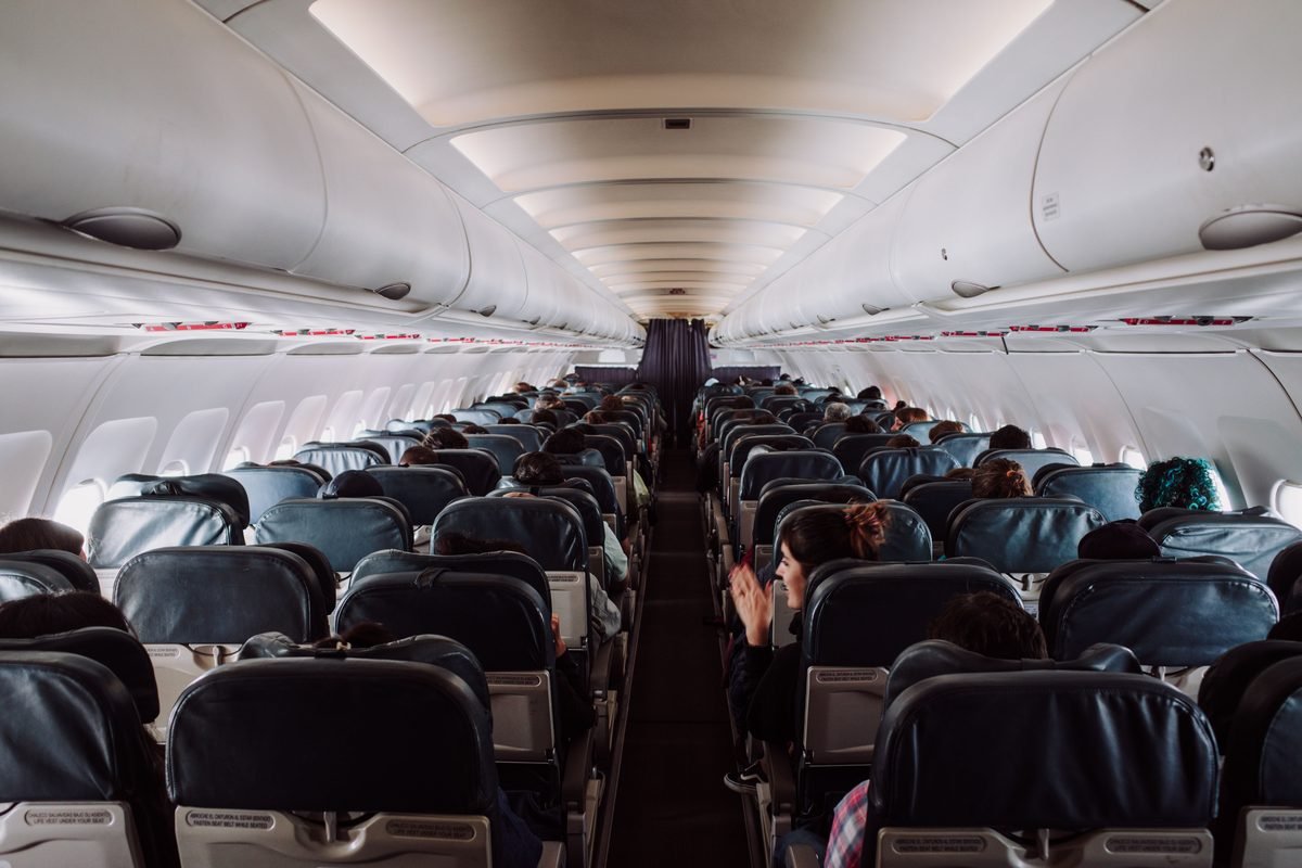 Passengers seated inside a commercial airplane cabin during flight.