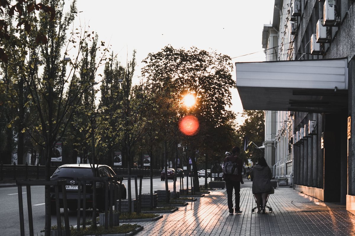 Evening street scene with pedestrians and sunset lighting.