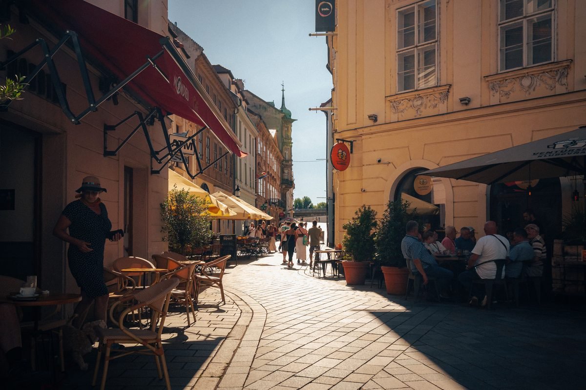 Bustling outdoor cafe terrace in the historic center of Bratislava during summer.