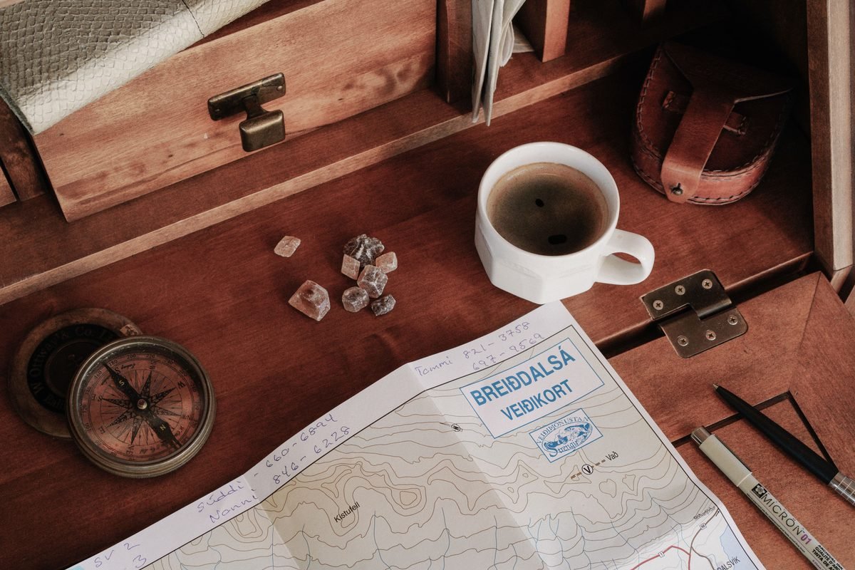 Rustic wooden desktop setup featuring a travel map, compass, and coffee cup.