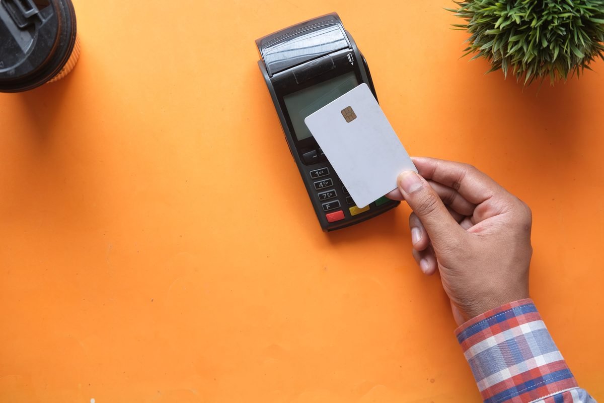 Hand making a contactless payment with a credit card on a reader.