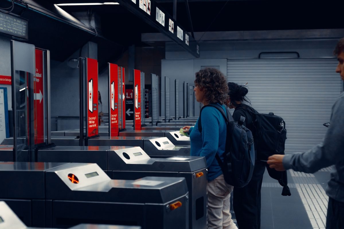 Commuters using automatic turnstiles at a metro station.