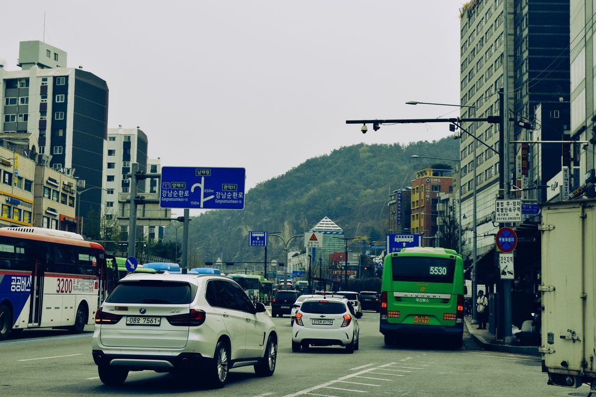 Traffic flow on a city street in Seoul with local signage.
