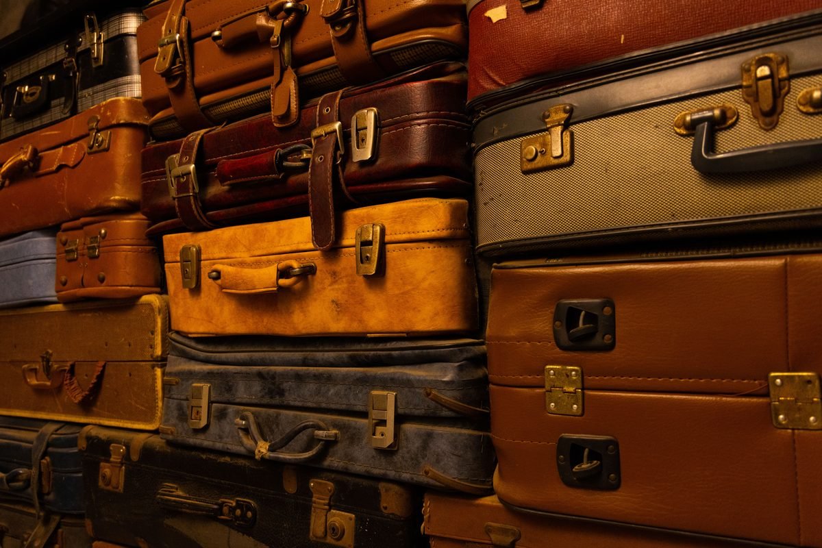 Stack of vintage and modern suitcases showcasing assorted textures.