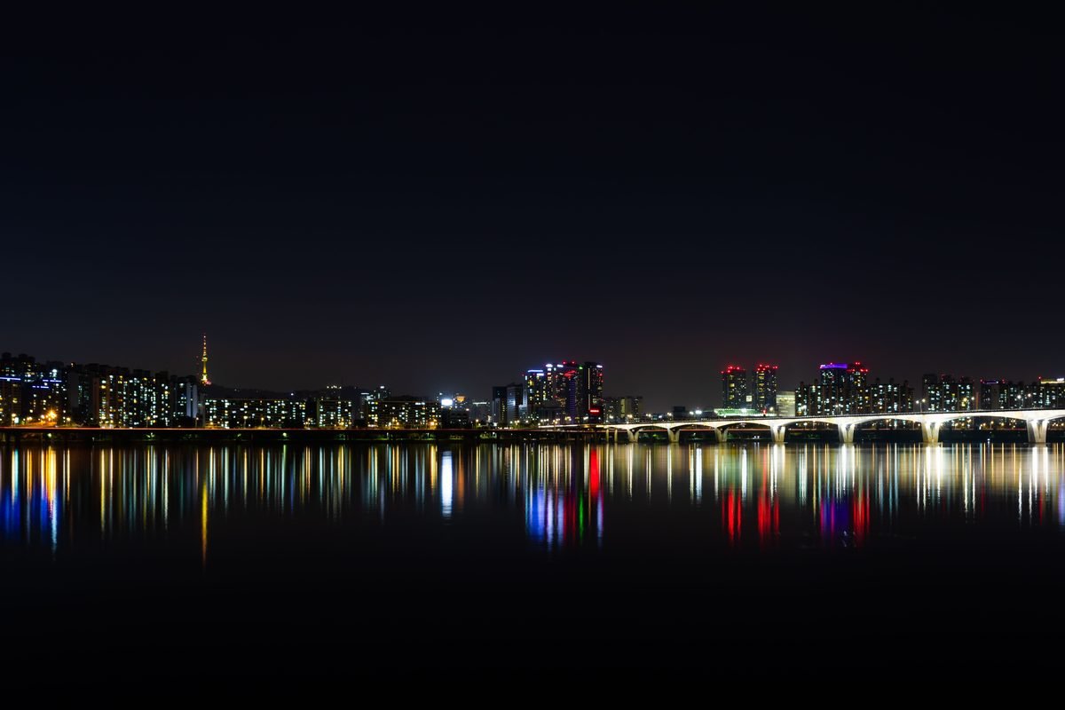 Illuminated city skyline and bridge reflected over the Han River in Seoul.