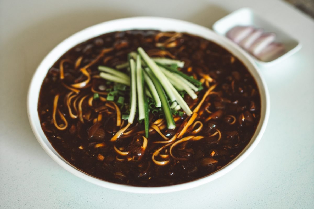 Bowl of Korean jjajangmyeon noodles topped with fresh cucumber strips.