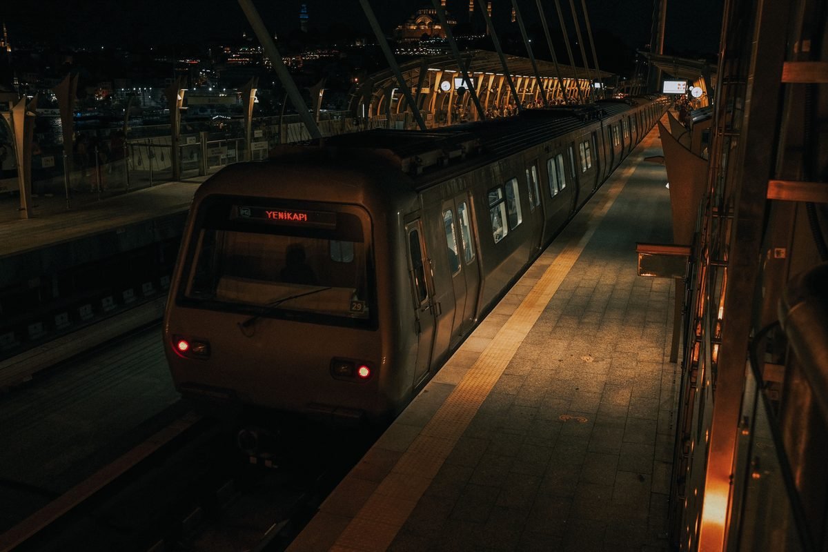 Metro train at a station in Istanbul at night with city lights.