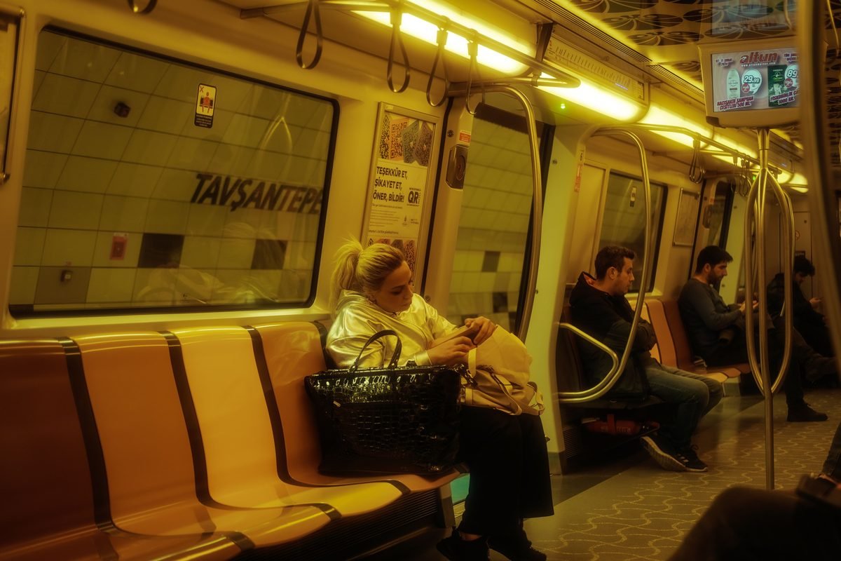Commuters sitting inside an Istanbul metro train interior.
