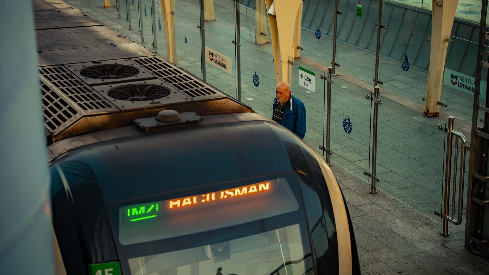 Metro train at an Istanbul station platform with waiting passenger.