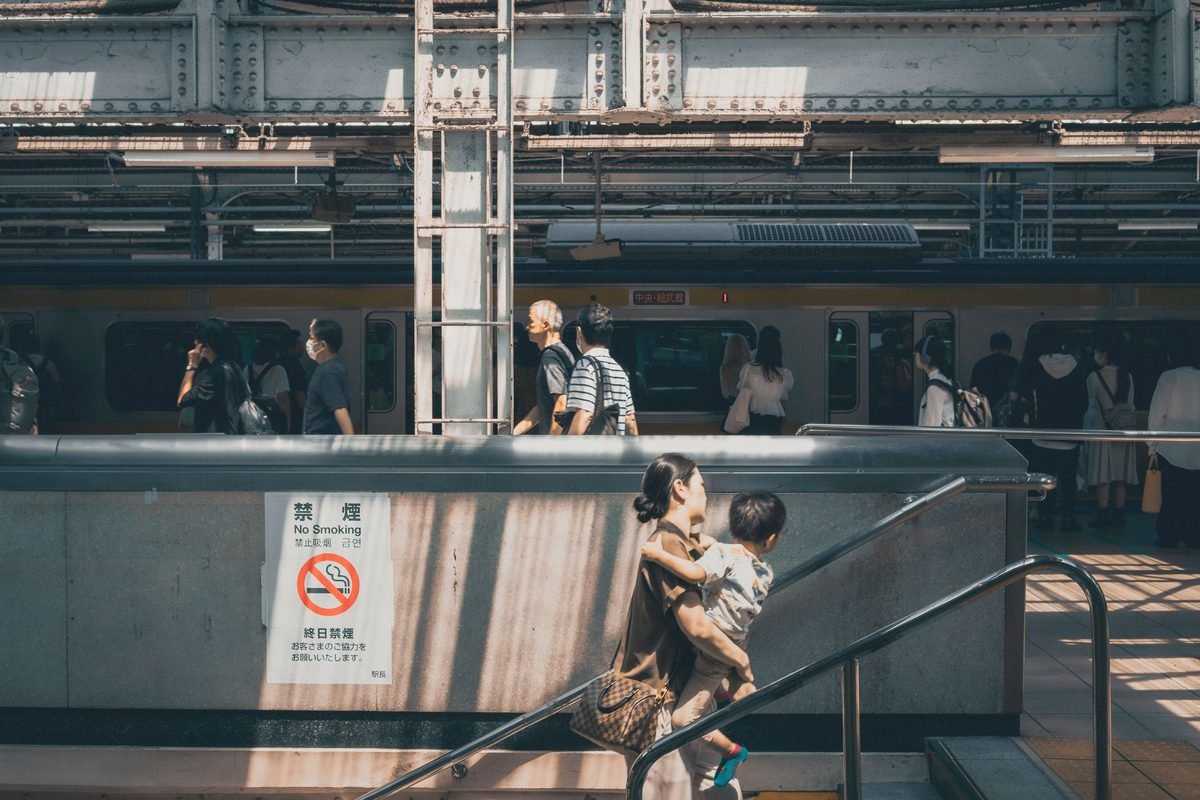 Commuters and mother with child at a busy Tokyo train station