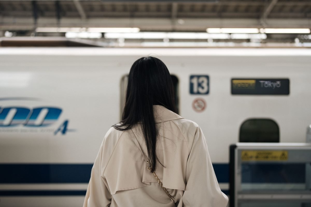 Woman waiting on platform next to a Shinkansen train