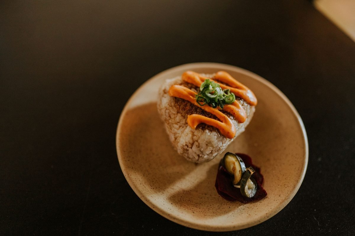 Japanese rice ball on a plate with spicy mayo and pickles
