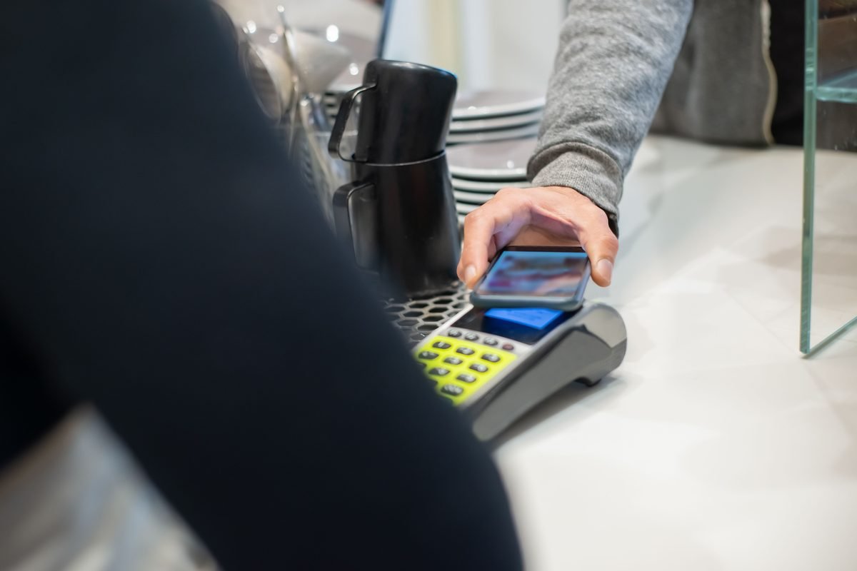 Customer making a contactless payment using a smartphone at a counter