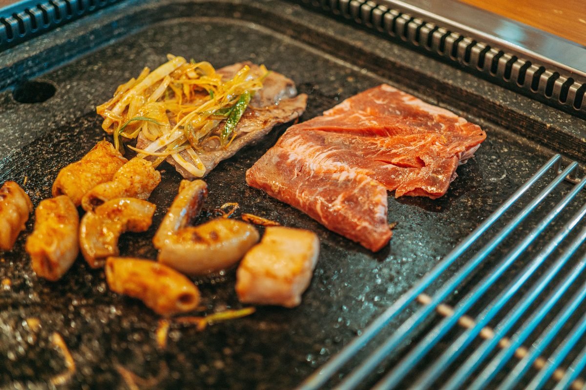 Assorted meats and vegetables cooking on a Korean barbecue grill