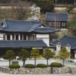 Elevated view of traditional Korean tiled roofs set against a natural hillside background.