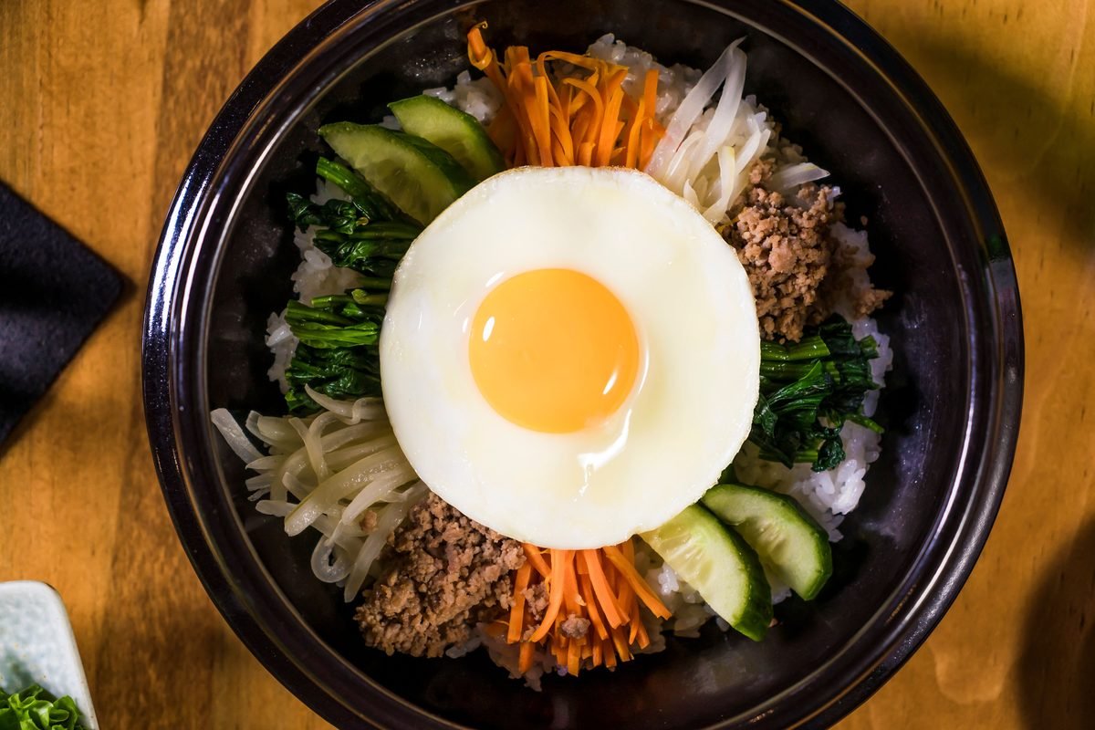 Overhead view of Korean bibimbap served with fresh vegetables and egg.