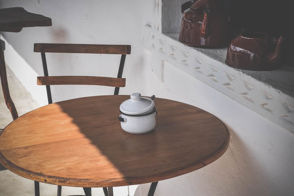 Rustic wooden table with ceramic kettle and brown teapots on a ledge.