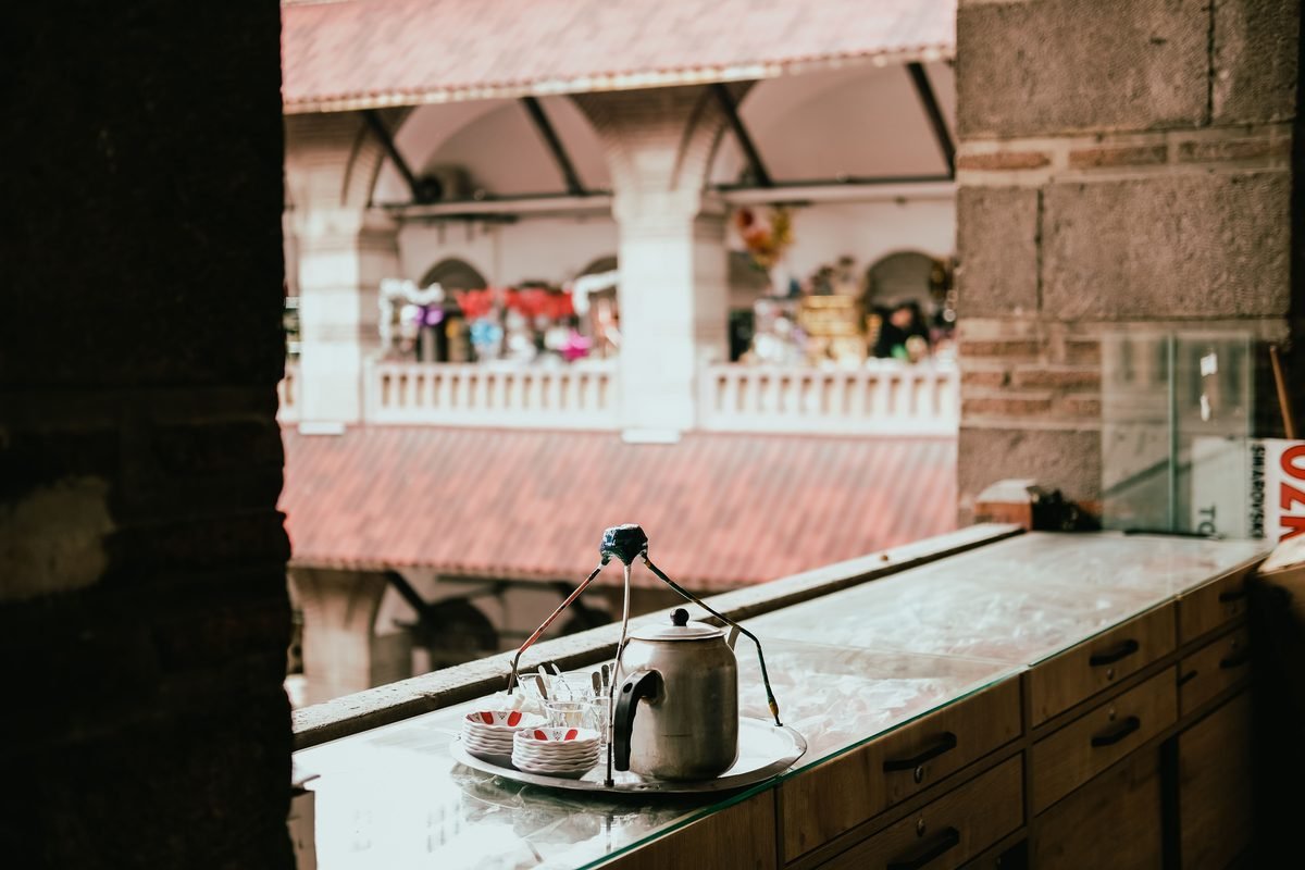 Metallic kettle and cups on a counter overlooking a traditional market.