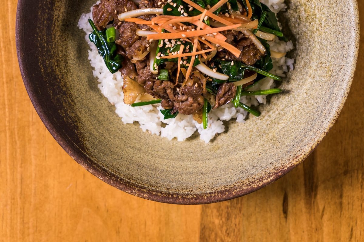 Korean Bibimbap with vegetables and beef in a rustic bowl