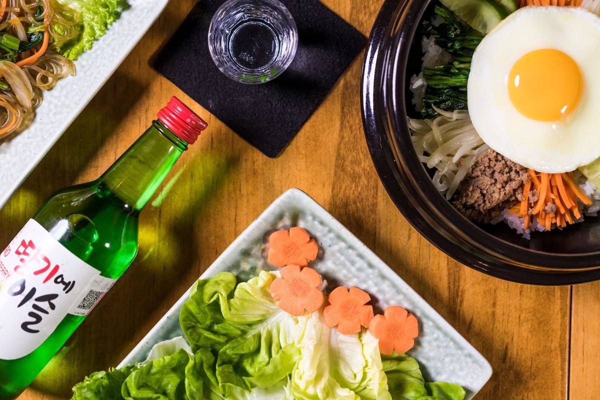Colorful display of Korean bibimbap with soju on a wooden table