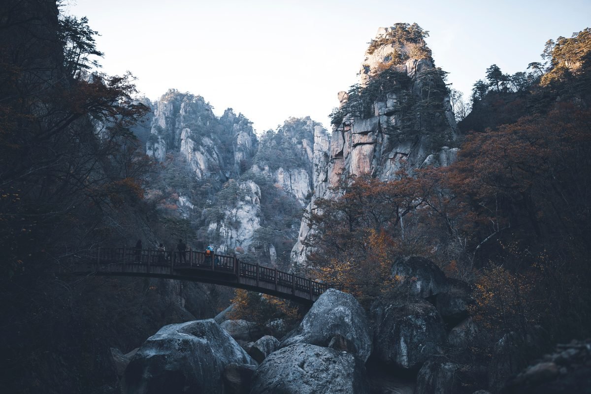 A serene bridge amidst autumn foliage and rugged mountains in Seoraksan National Park.