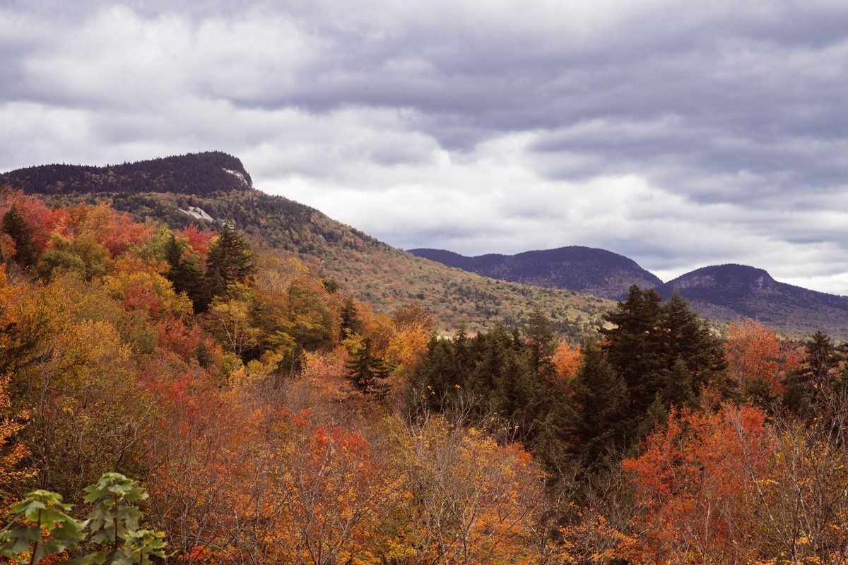 Vibrant fall foliage in a stunning mountain landscape under a dramatic cloudy sky