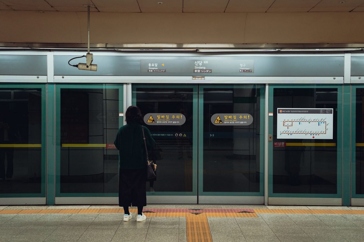 A passenger waits on the platform at a modern subway station in South Korea.