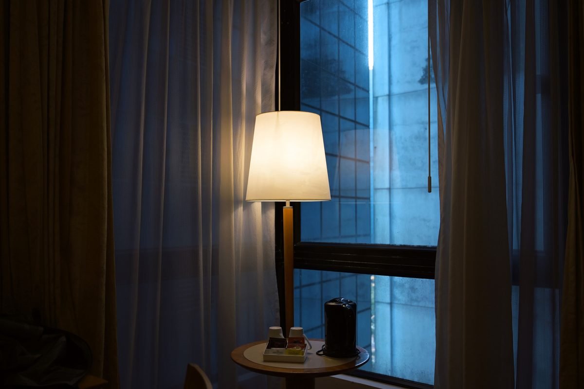 Warmly lit room with a glowing lamp and urban cityscape