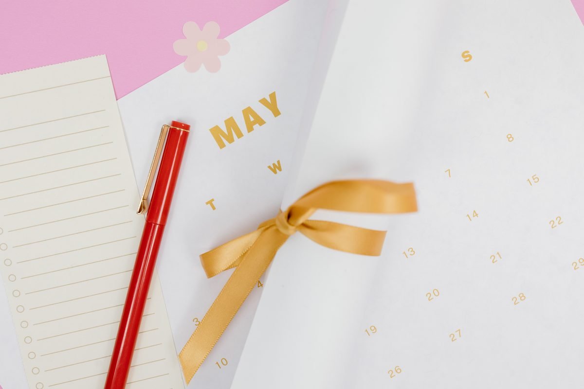 Flat lay of a calendar with a red pen and ribbon