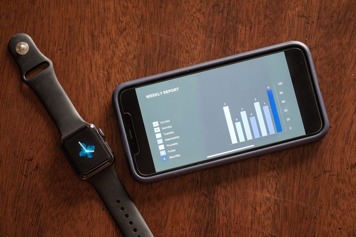 Close-up of a smartphone and smartwatch displaying data on a wooden table