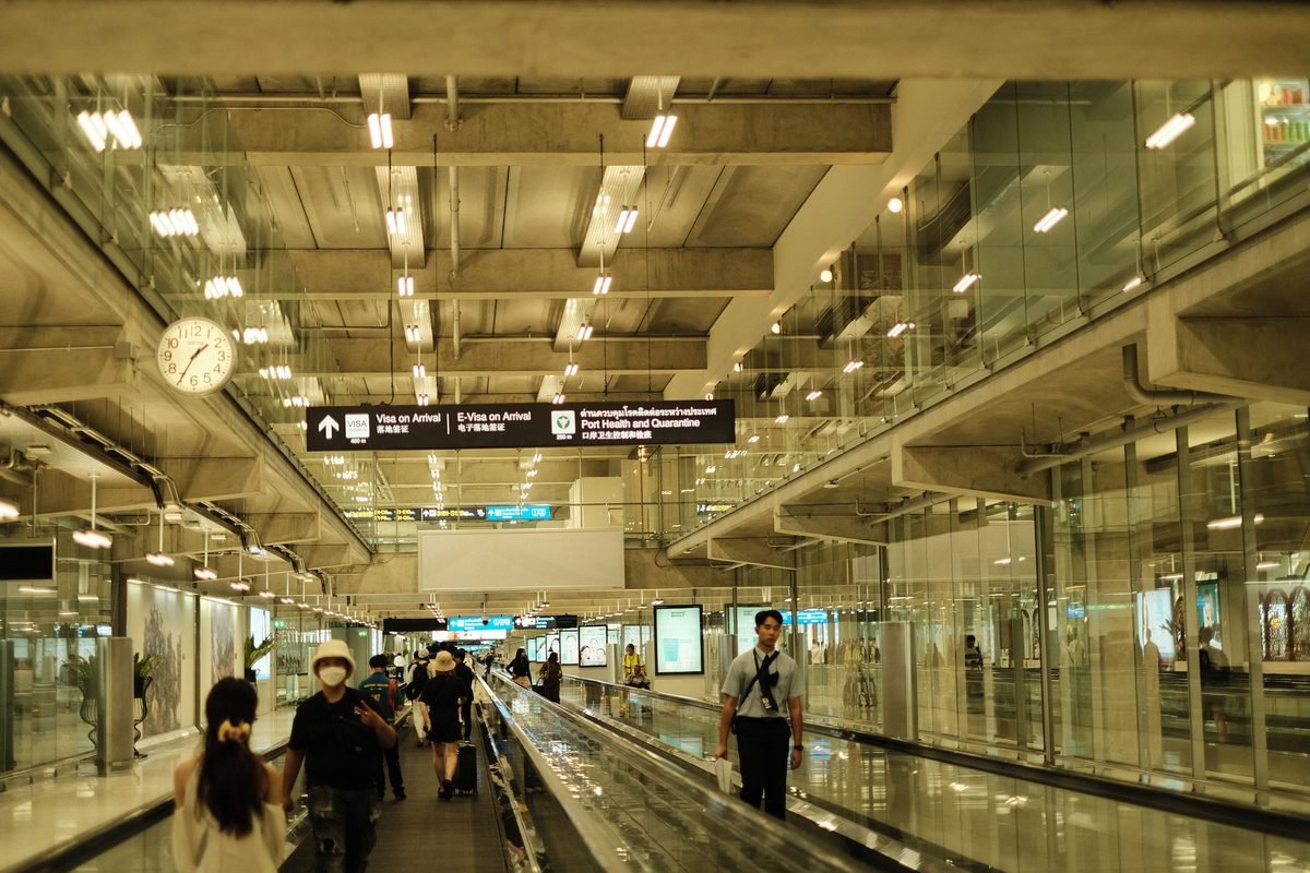Passengers walking in a well-lit modern airport terminal with glass design