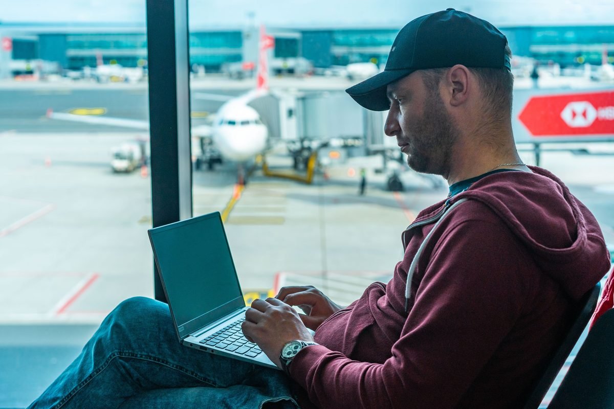 A man working on his laptop in an airport terminal with a plane outside