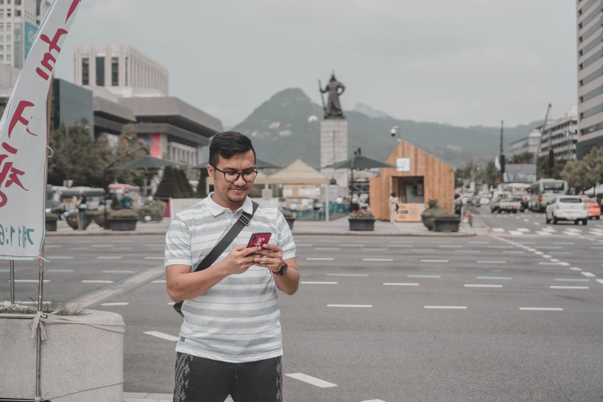 A man using a smartphone on a city street with traditional elements