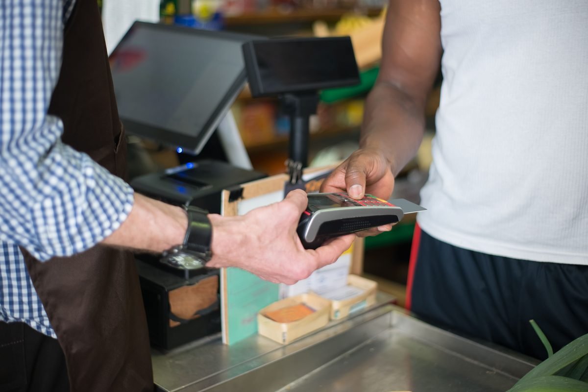 Customer making a contactless payment with a credit card at a store checkout.