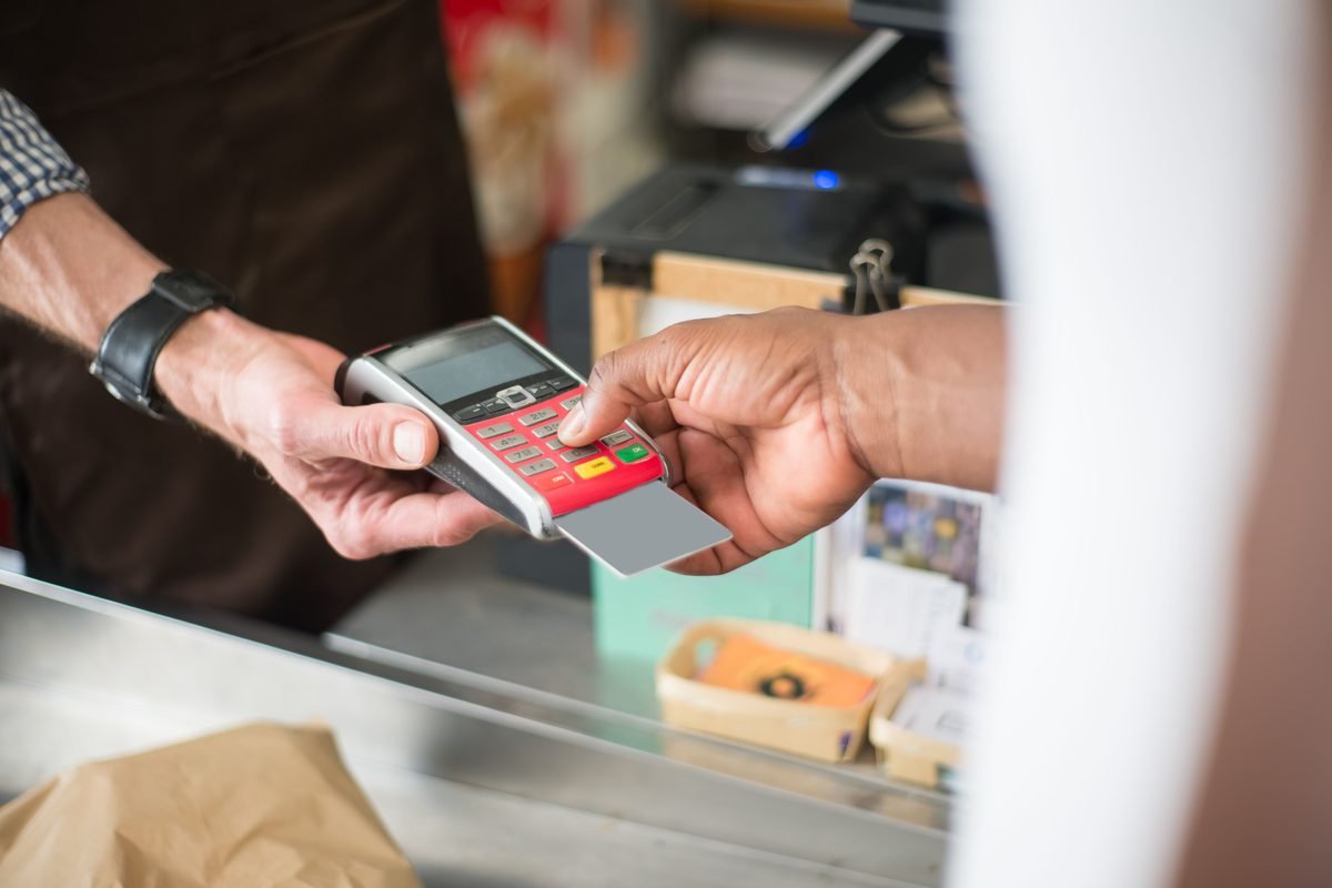 Customer using a card for contactless payment at a retail store checkout.