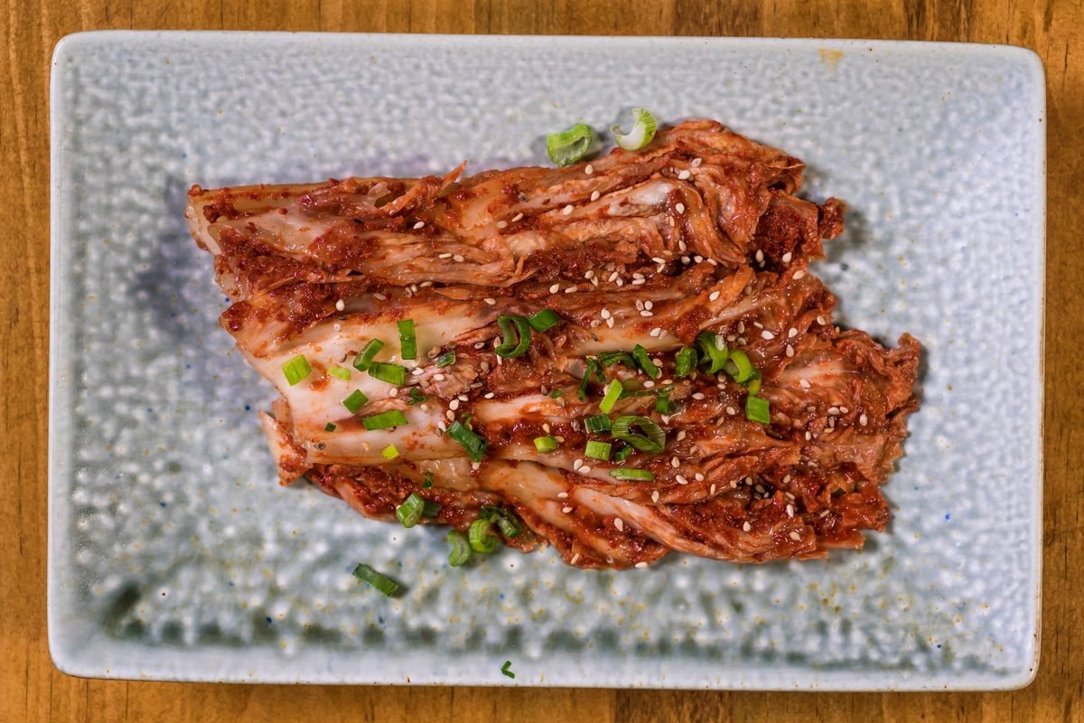 Close-up of fresh homemade kimchi garnished with green onions and sesame seeds.