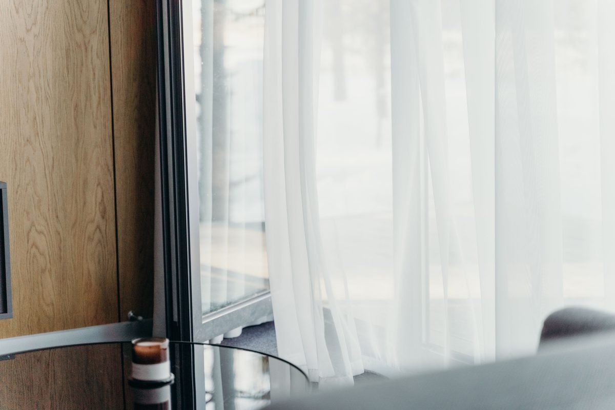 Modern hotel room with sheer curtains and minimalist luxury decor.