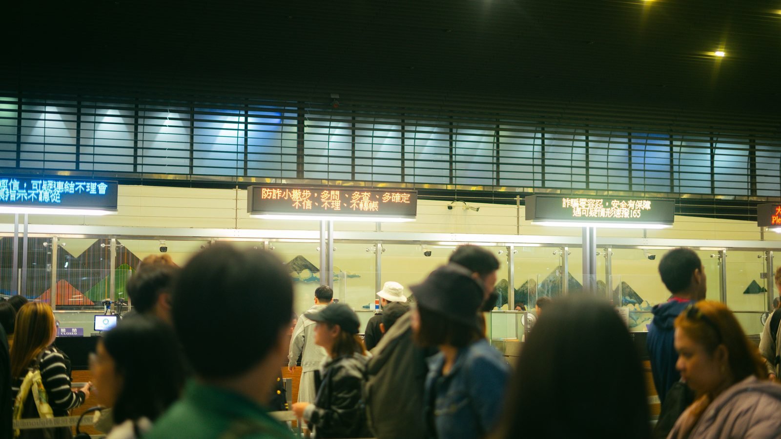 Travelers queue near airport information boards with digital signs.