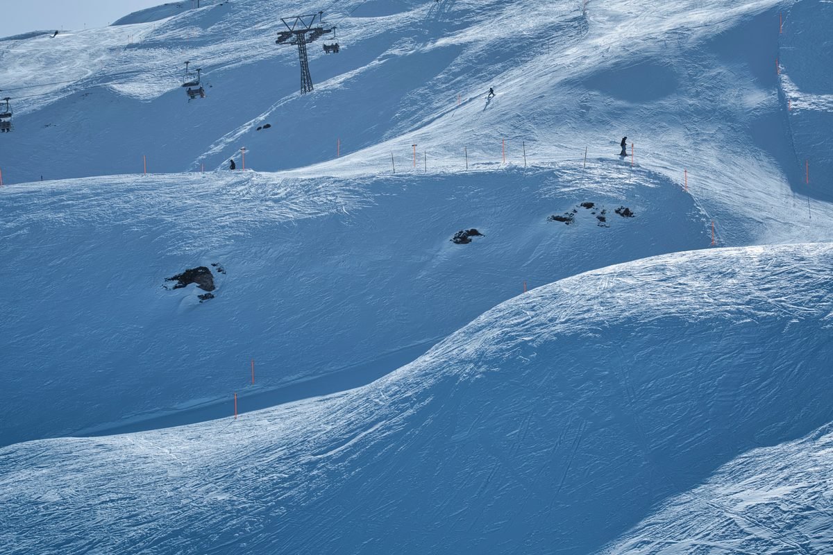Scenic view of a snowy ski resort slope with chairlifts under clear winter sky