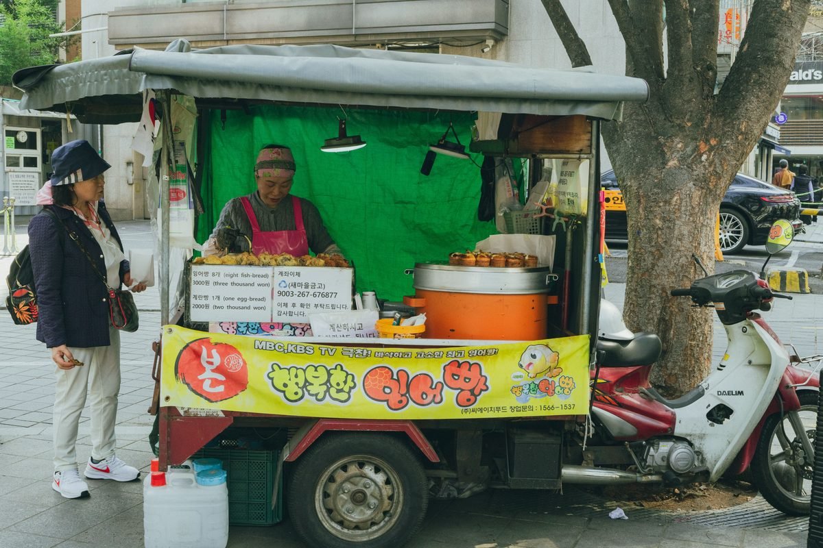 Street food stall selling fish-shaped pastries in Seoul with customer waiting