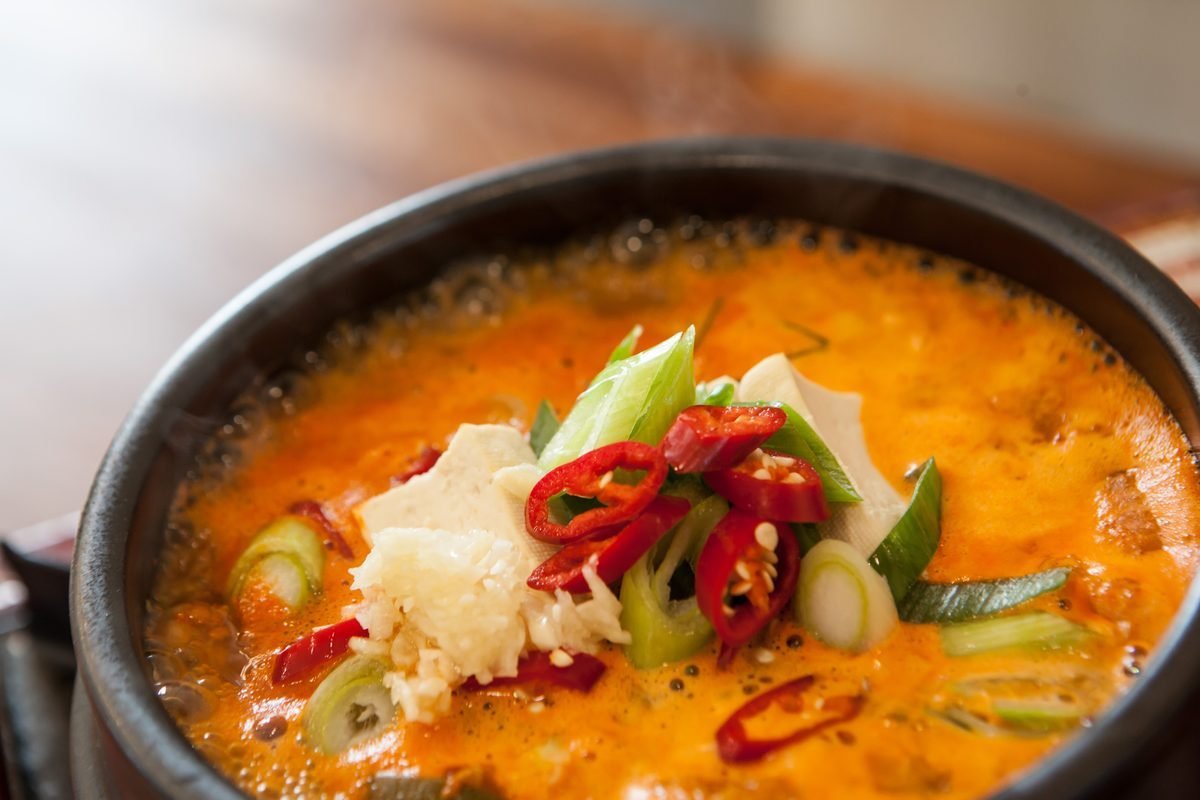Bubbling doenjang-jjigae soybean paste stew with tofu and chili in a stone pot