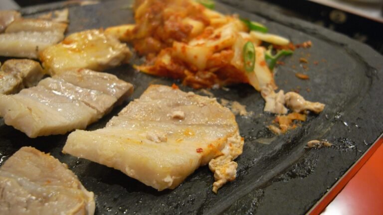 Pork belly and kimchi grilling on a stone plate at a Korean barbecue restaurant